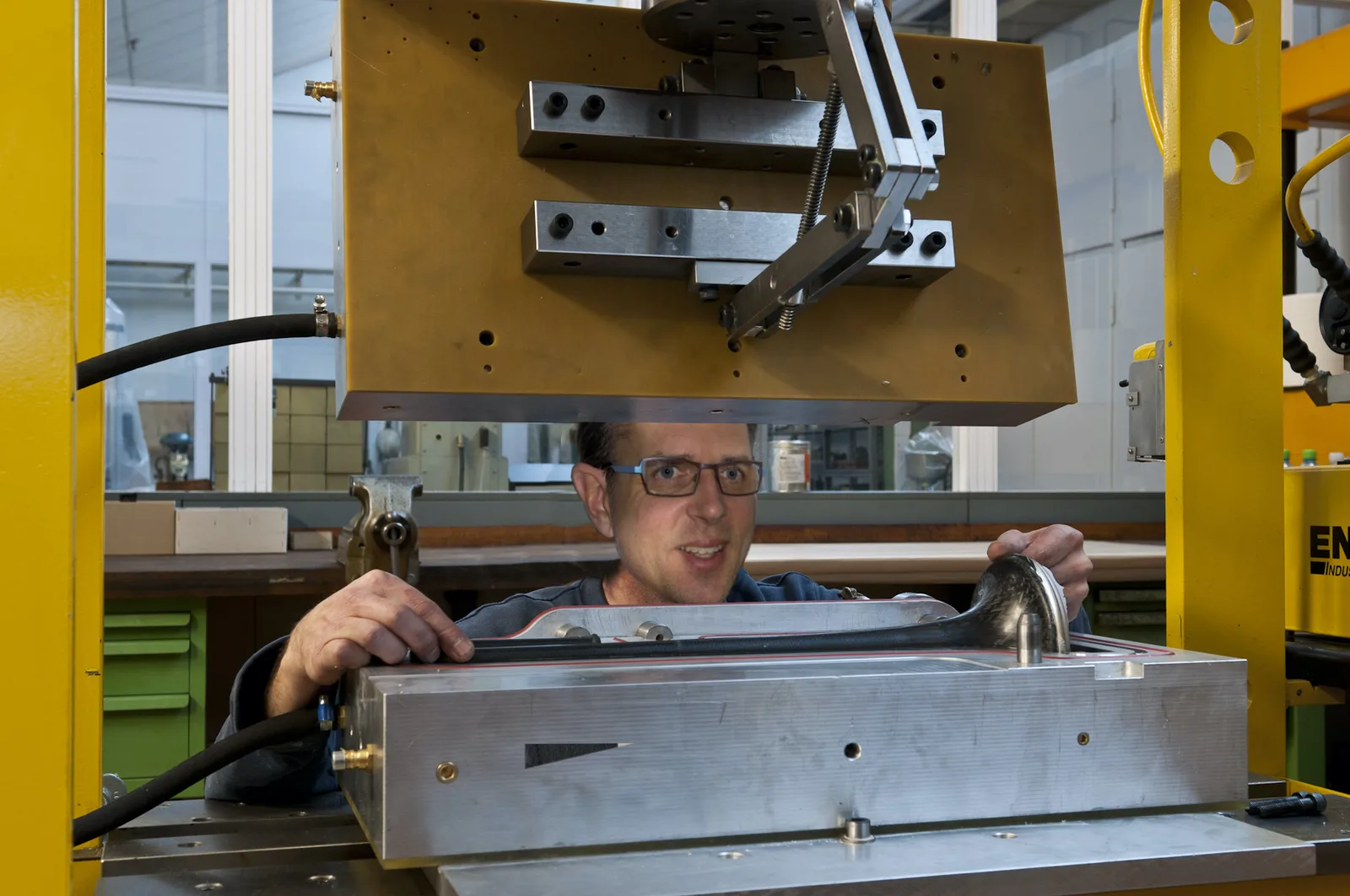 A worker places a carbon bell into the open mould of the workshop press
